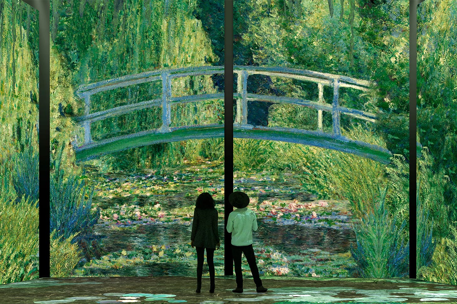 Two people standing in front of a large display of a bridge and water